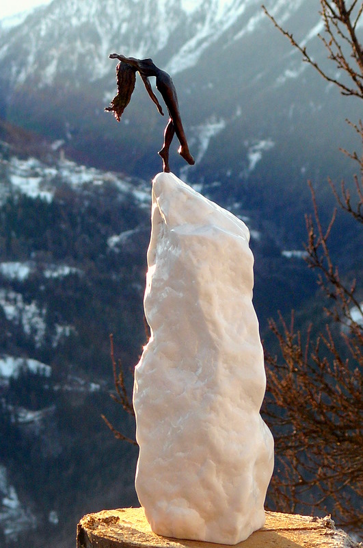 Vue en pied de la sculpture Audacieuse pesanteur, bronze et albâtre. Fond de paysage de montagne hivernal.